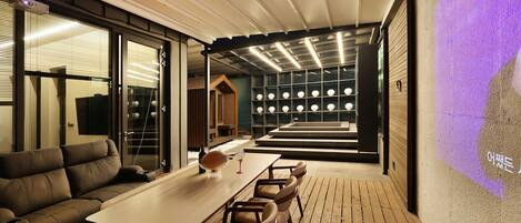 Een modern interieur met een houten terras, een bank, een tafel en een projectiescherm.