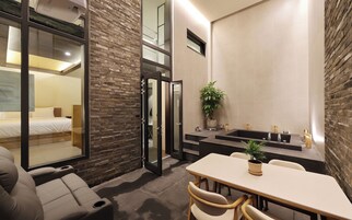 Una habitación de hotel moderna con cama, zona de estar y baño con lavabo y espejo.