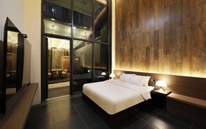 A modern hotel room with a large bed, bedside tables, a wooden accent wall, and a glass door leading to a dining area. - Brown Dot Hotel Dongtan (Hwaseong)