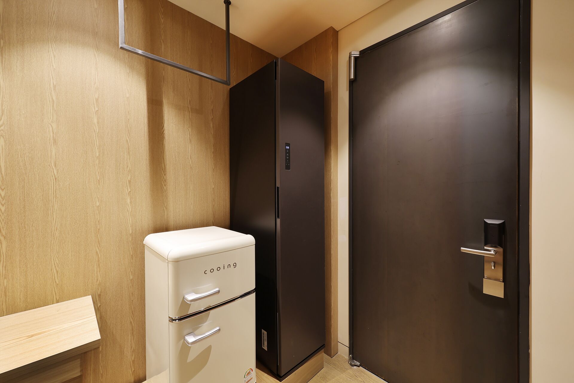 A compact room with a wooden wall, a white appliance, and a dark door.