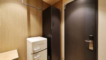 A compact room with a wooden wall, a white appliance, and a dark door.