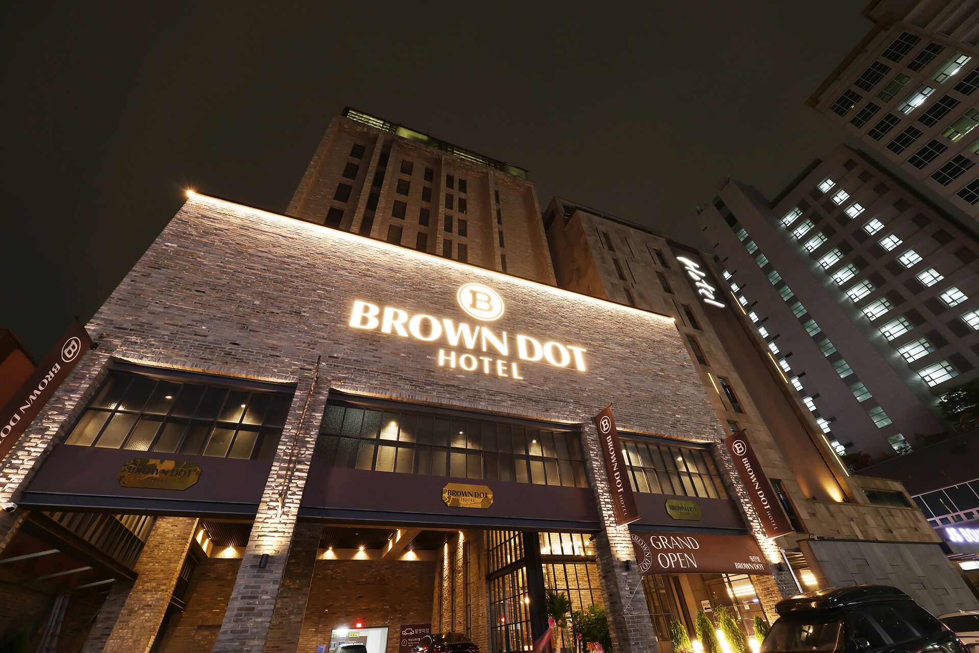 A Brown Dot Hotel with a prominent sign, brick facade, and multiple windows.