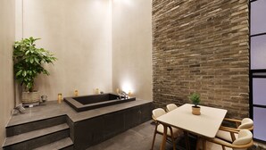 Un bagno moderno con una vasca, un tavolino con sedie e una pianta in vaso.