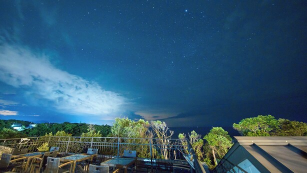 A night view of a terrace with outdoor seating, a railing, and a backdrop of a starry sky. - HOTEL HOLISTIC RESORT (Taiji)
