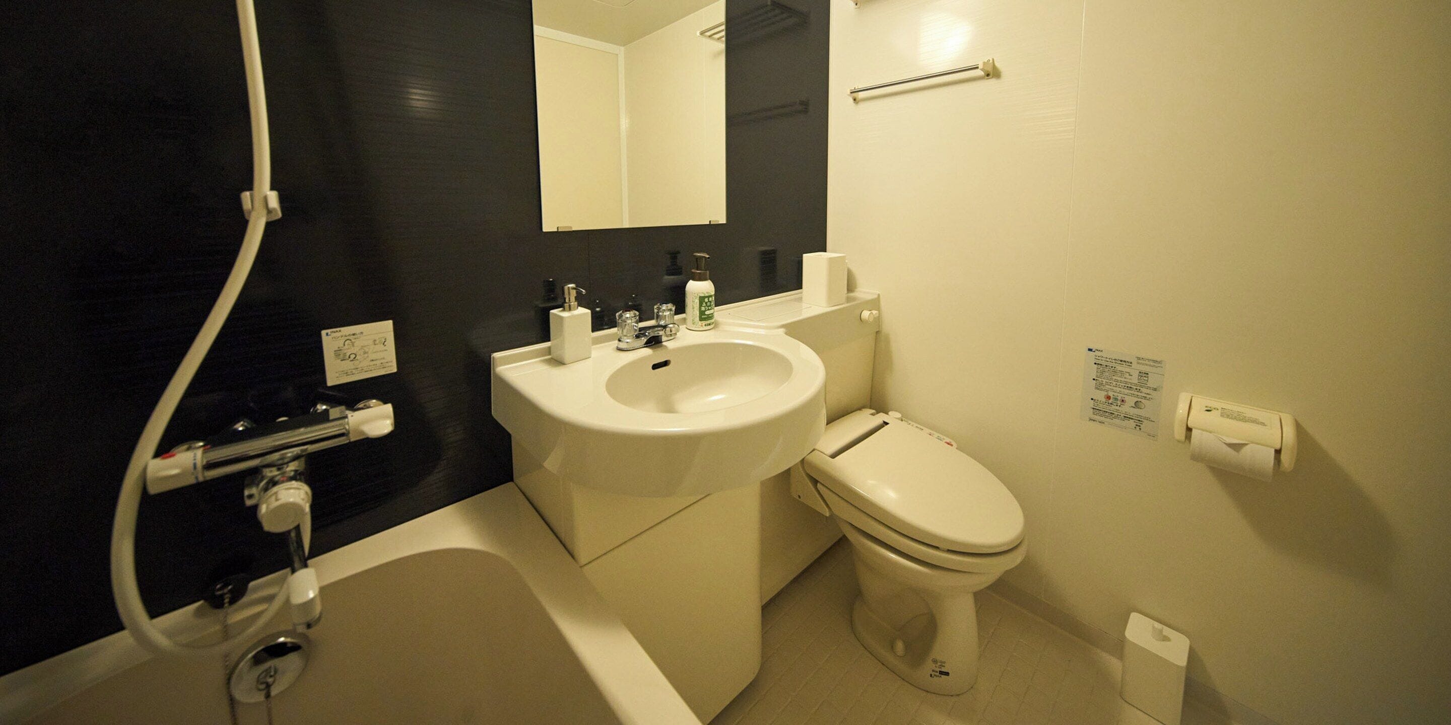 A bathroom with a white sink, toilet, and bathtub. There is a mirror above the sink and a towel rack on the wall.