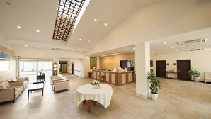 A spacious hotel lobby with a reception desk, seating area, and a large window providing natural light. - HOTEL HOLISTIC RESORT (Taiji)