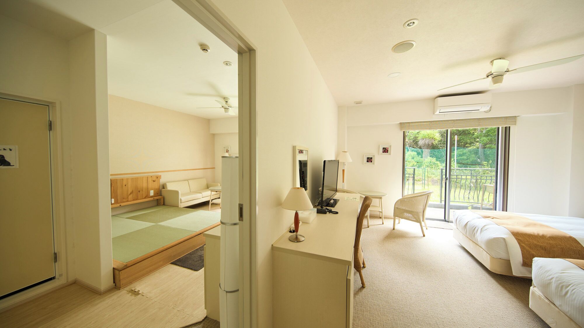 A hotel room with a bed, a desk, a chair, a sofa, and a view of the outdoors.