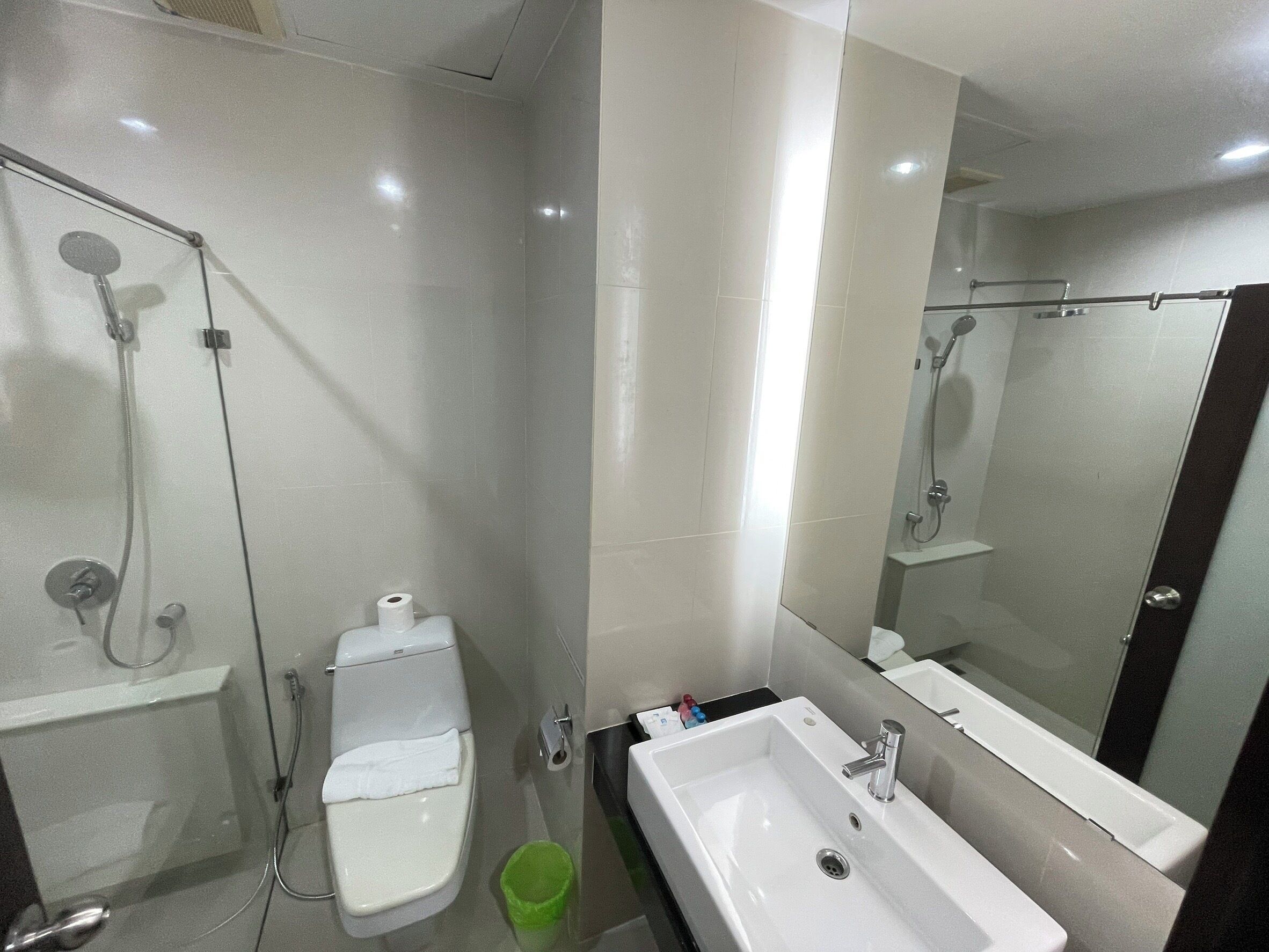 A modern bathroom with a toilet, bidet, sink, and mirror.