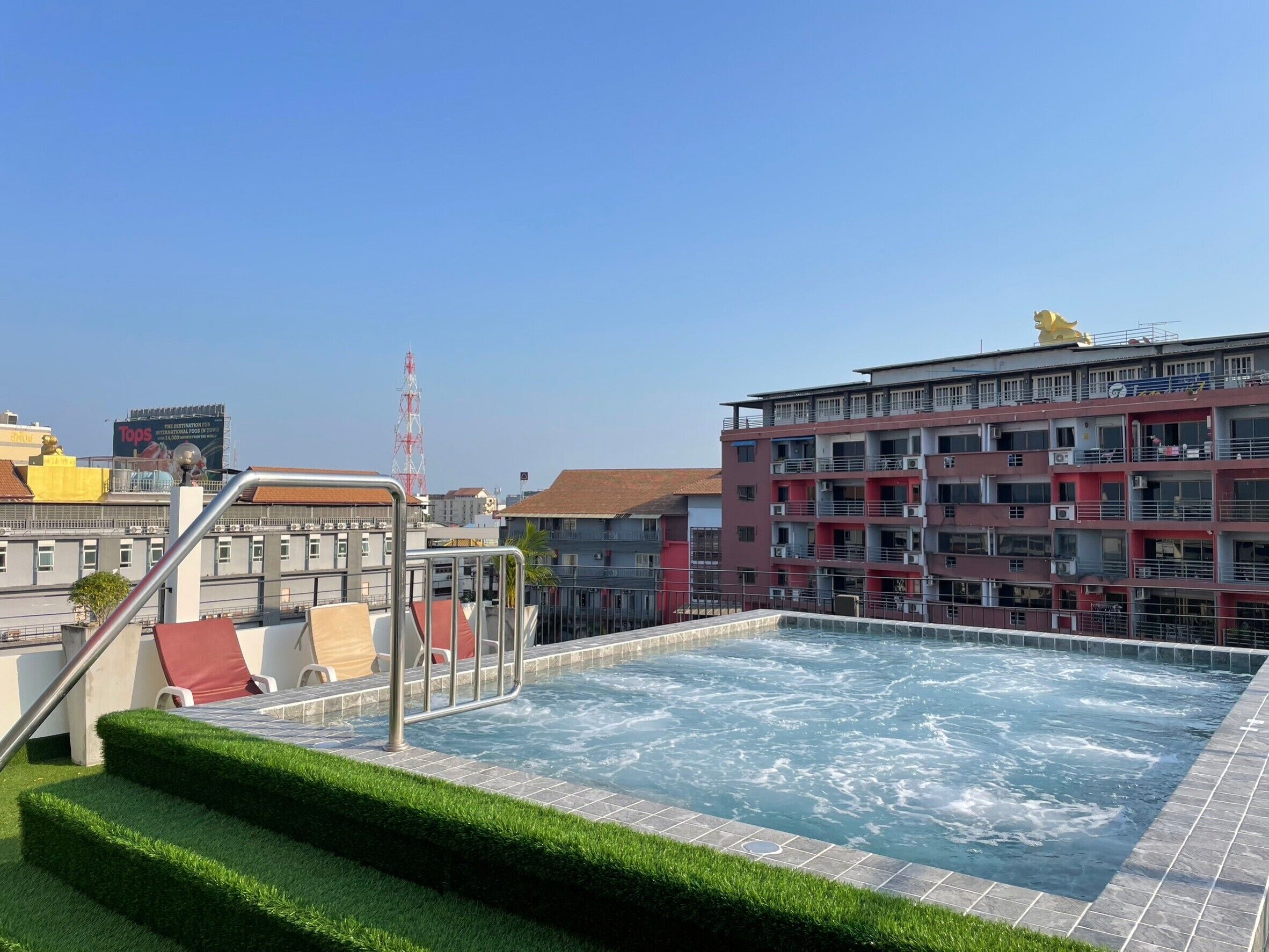 A rooftop swimming pool with a view of a multi-story building in the background.