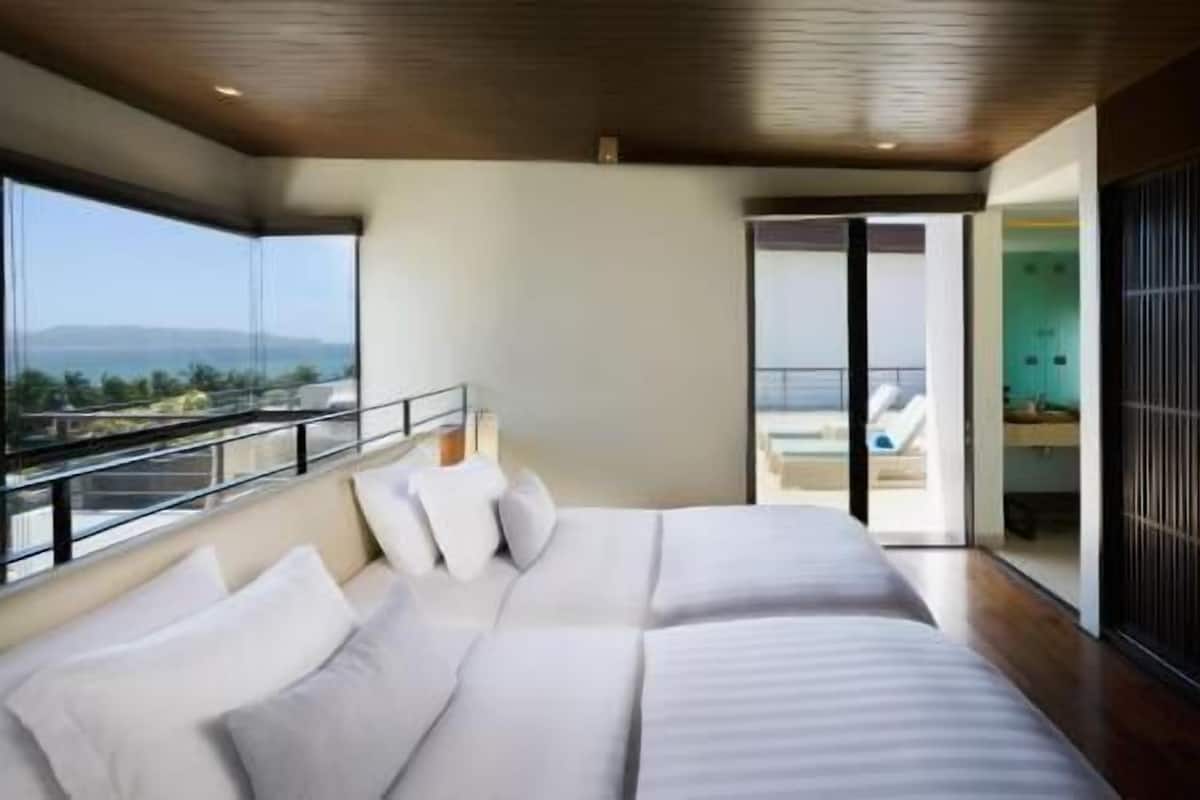 A modern bedroom with a large bed, a balcony with a view, and a sliding door leading to a bathroom.