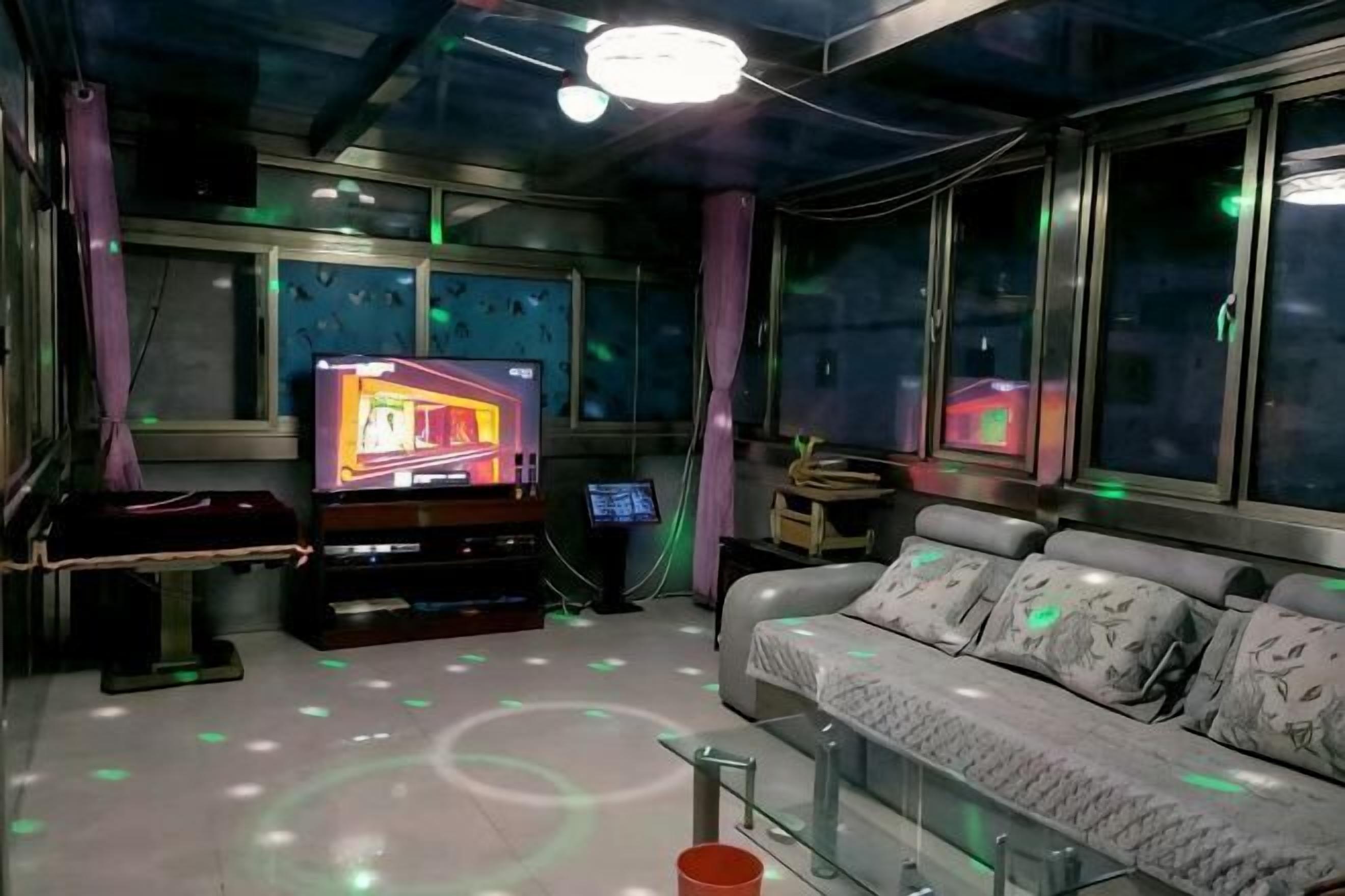 A room with a TV, sofa, and windows.
