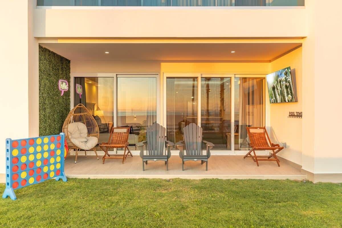 Un edificio moderno con un'area salotto esterna coperta, porte in vetro e un tetto piatto.