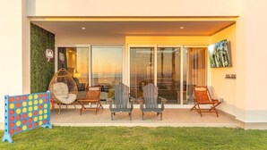 A modern building with a covered outdoor seating area, glass doors, and a flat roof. - Encantame Towers | Ground Floor| Lazy River| Pool (Playa Encanto)
