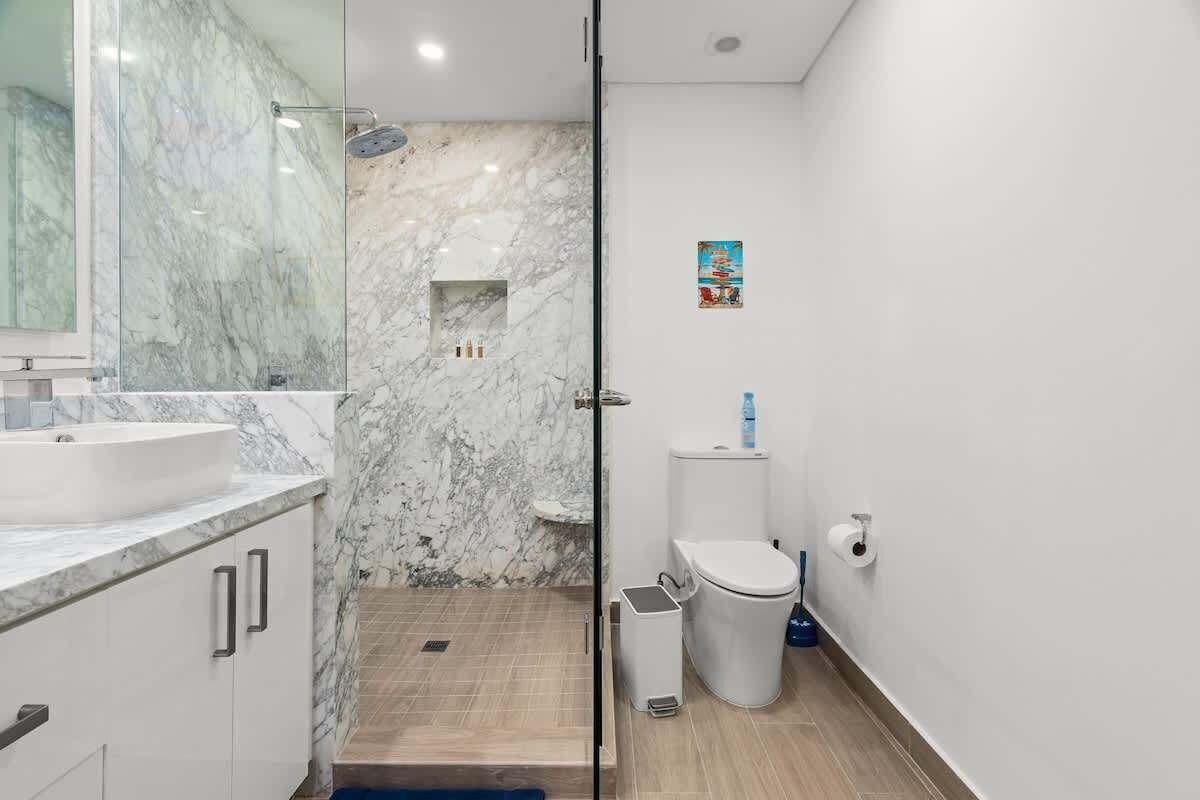 Un bagno con un lavandino in marmo, una cabina doccia in vetro e un water.
