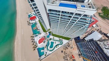A high-rise hotel with a rooftop pool, adjacent to a beach.