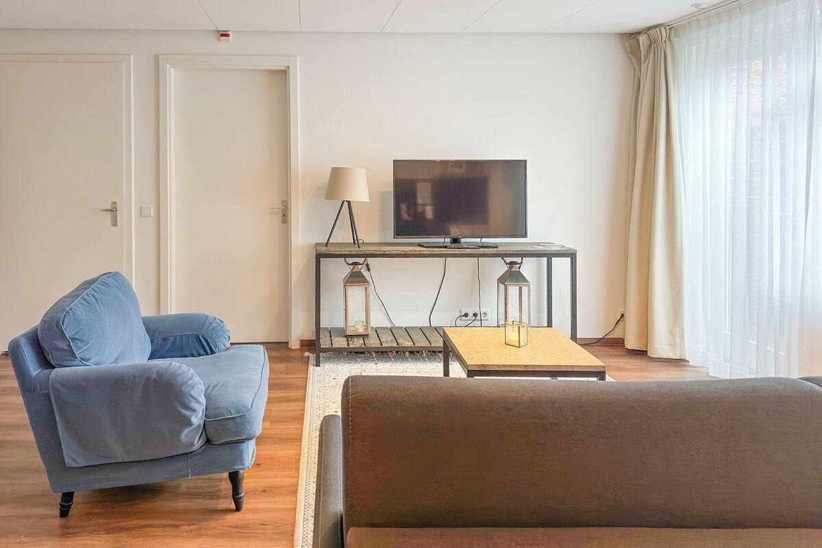 A modern living room with a sofa, a coffee table, a TV on a stand, and a lamp.