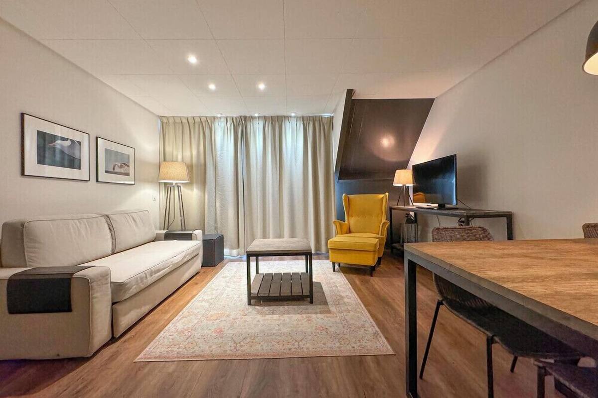 A modern living room with a sofa, a yellow armchair, a coffee table, a TV, and a dining table.
