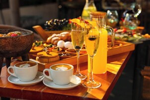 A breakfast buffet with coffee cups, a pitcher of orange juice, and a variety of pastries.
