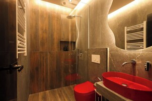 Une salle de bain moderne avec une douche à parois de verre, un lavabo rouge et un porte-serviettes.