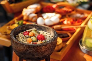A wooden bowl filled with oatmeal topped with fruits and seeds.