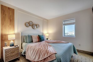 A bedroom with a bed, bedside tables, a window, and a wall with a decorative mirror.