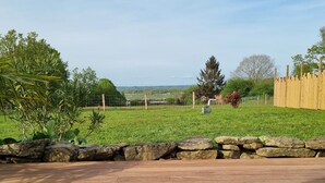 A wooden deck with a stone wall and a grassy area with a wooden fence.