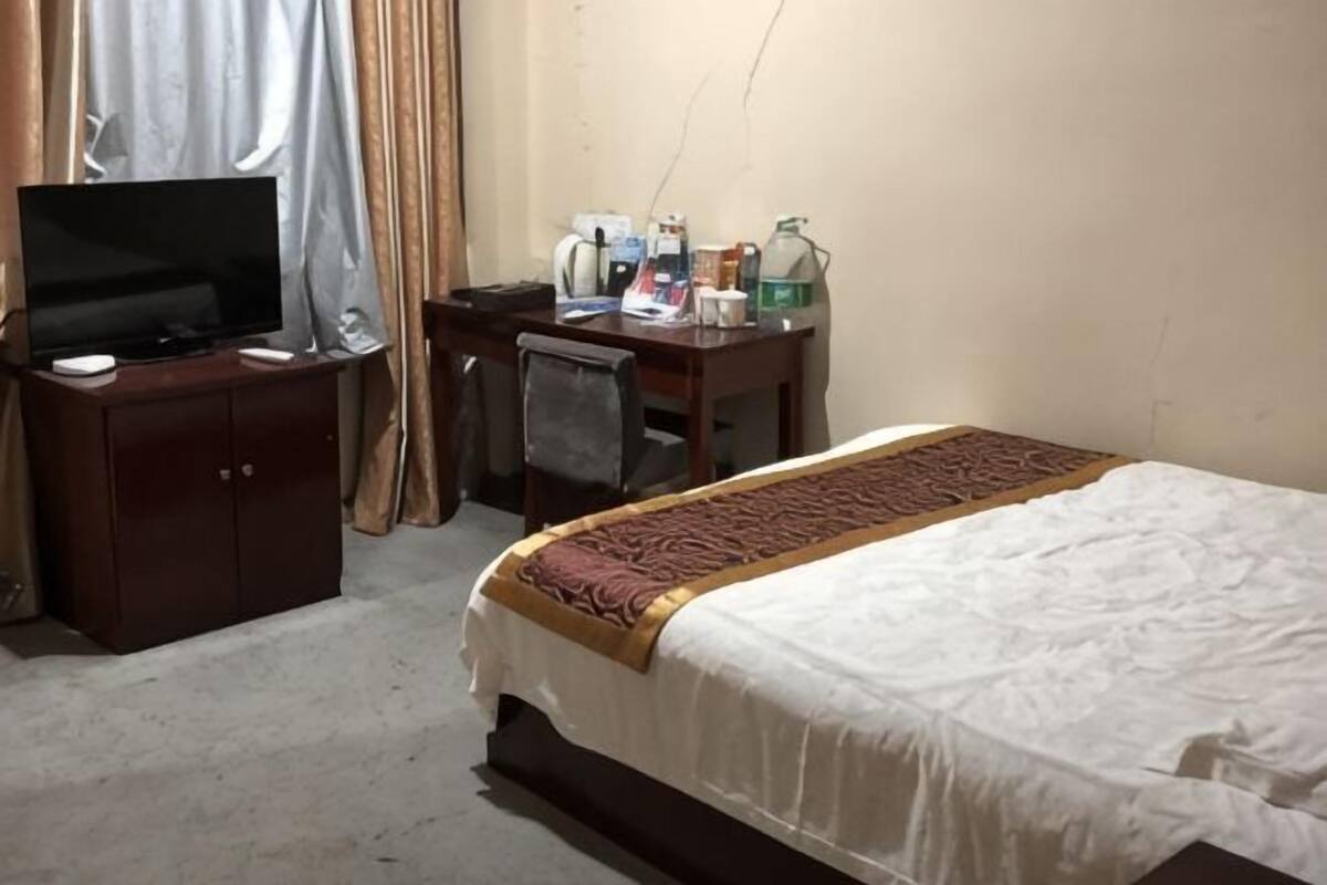 Habitación de hotel con cama, escritorio con televisor, silla y mesita con artículos de aseo.