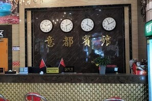 A reception desk with clocks, a sign with Chinese characters, and a potted plant. - Yidu Business Hotel, Weinan (Funan)