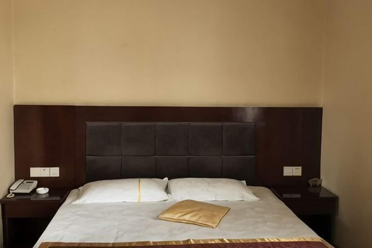 Una habitación de hotel con una cama grande, dos mesitas de noche y un cabecero.