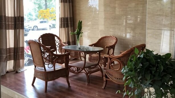 Una habitación con piso de madera, una mesa redonda con sillas, una planta en maceta y vistas al exterior.