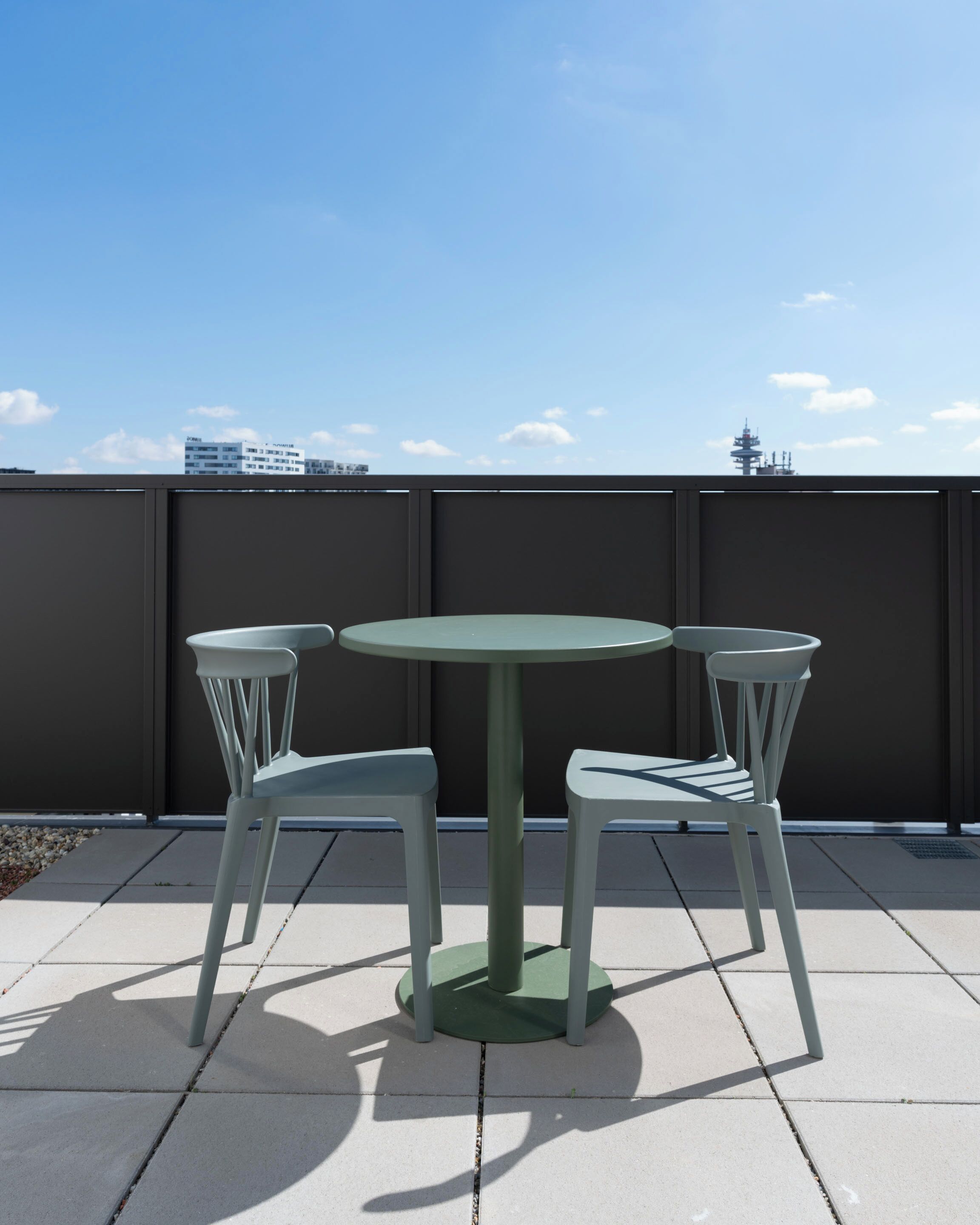 A round table with two chairs on a rooftop terrace.