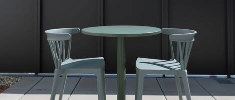 A round table with two chairs on a rooftop terrace.