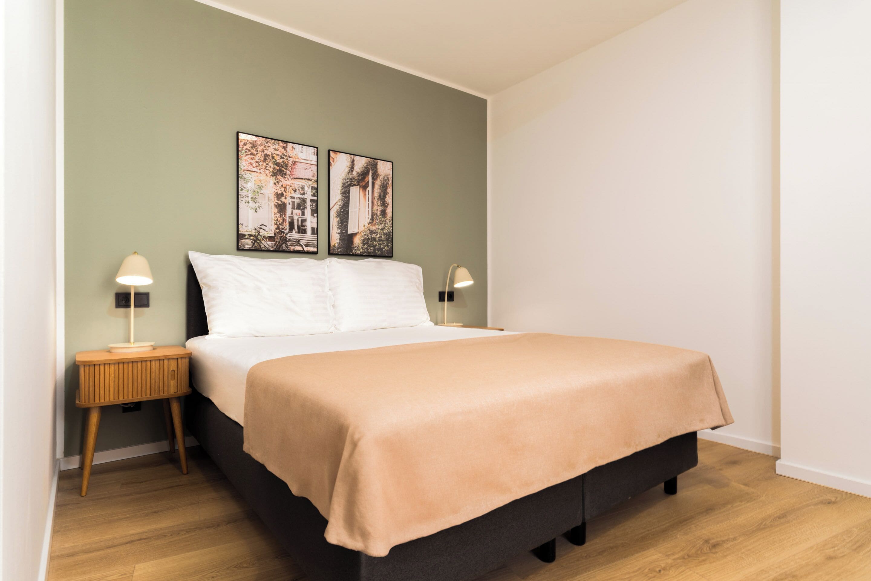 A bedroom with a bed, two bedside tables, and two wall-mounted lamps.