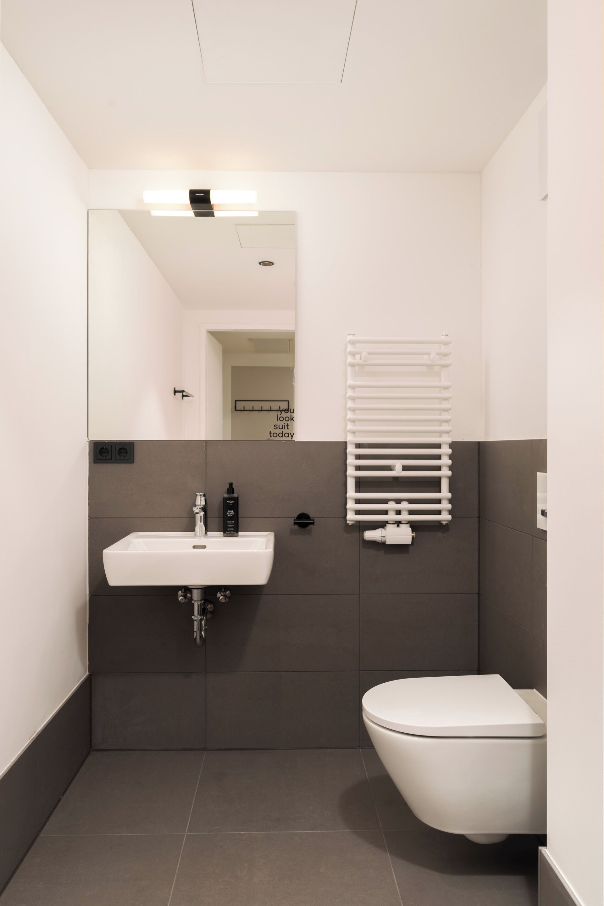 Une salle de bain moderne avec un lavabo blanc, des toilettes et un porte-serviettes.