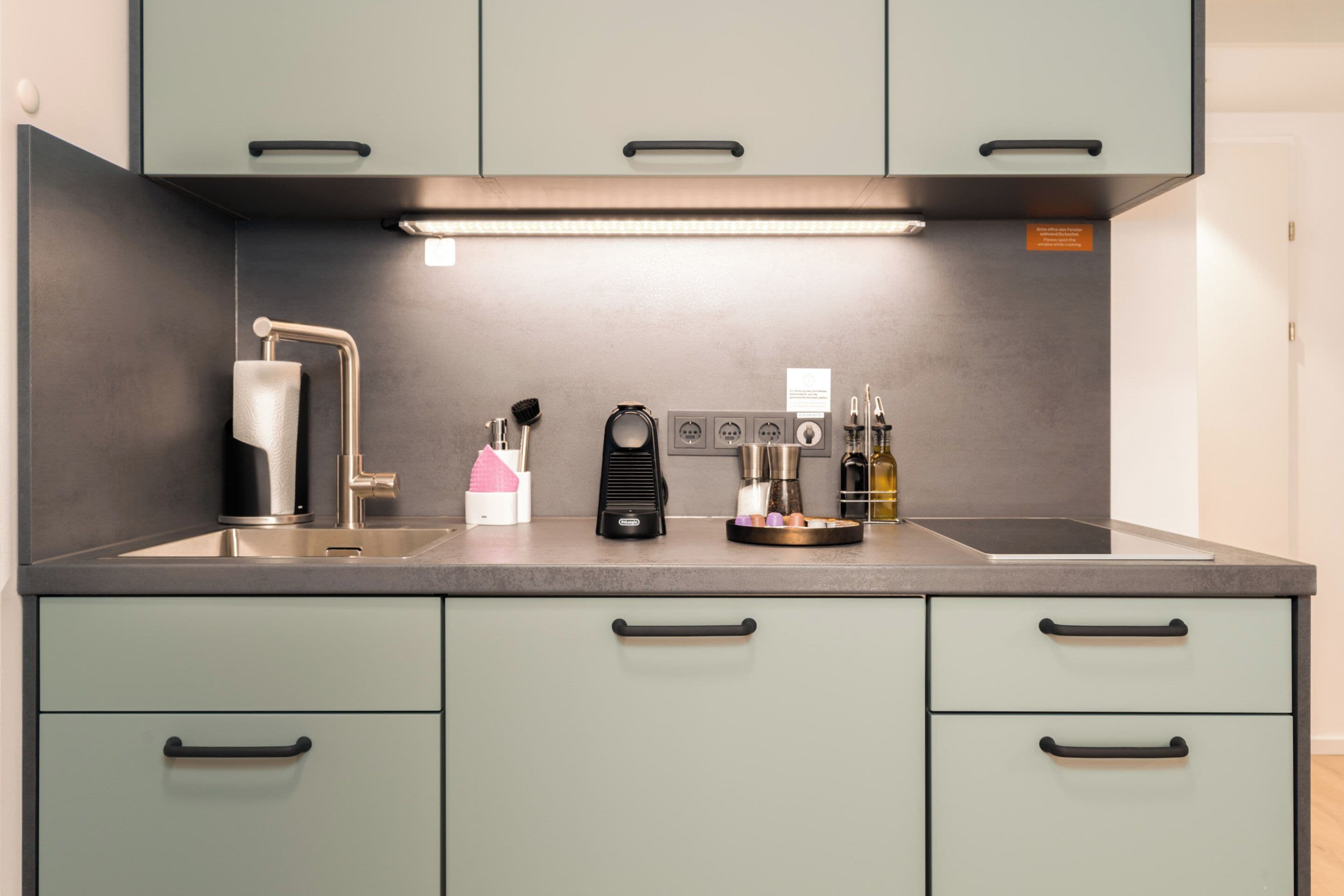 A modern kitchen with a stainless steel sink, a coffee machine, and a range hood.