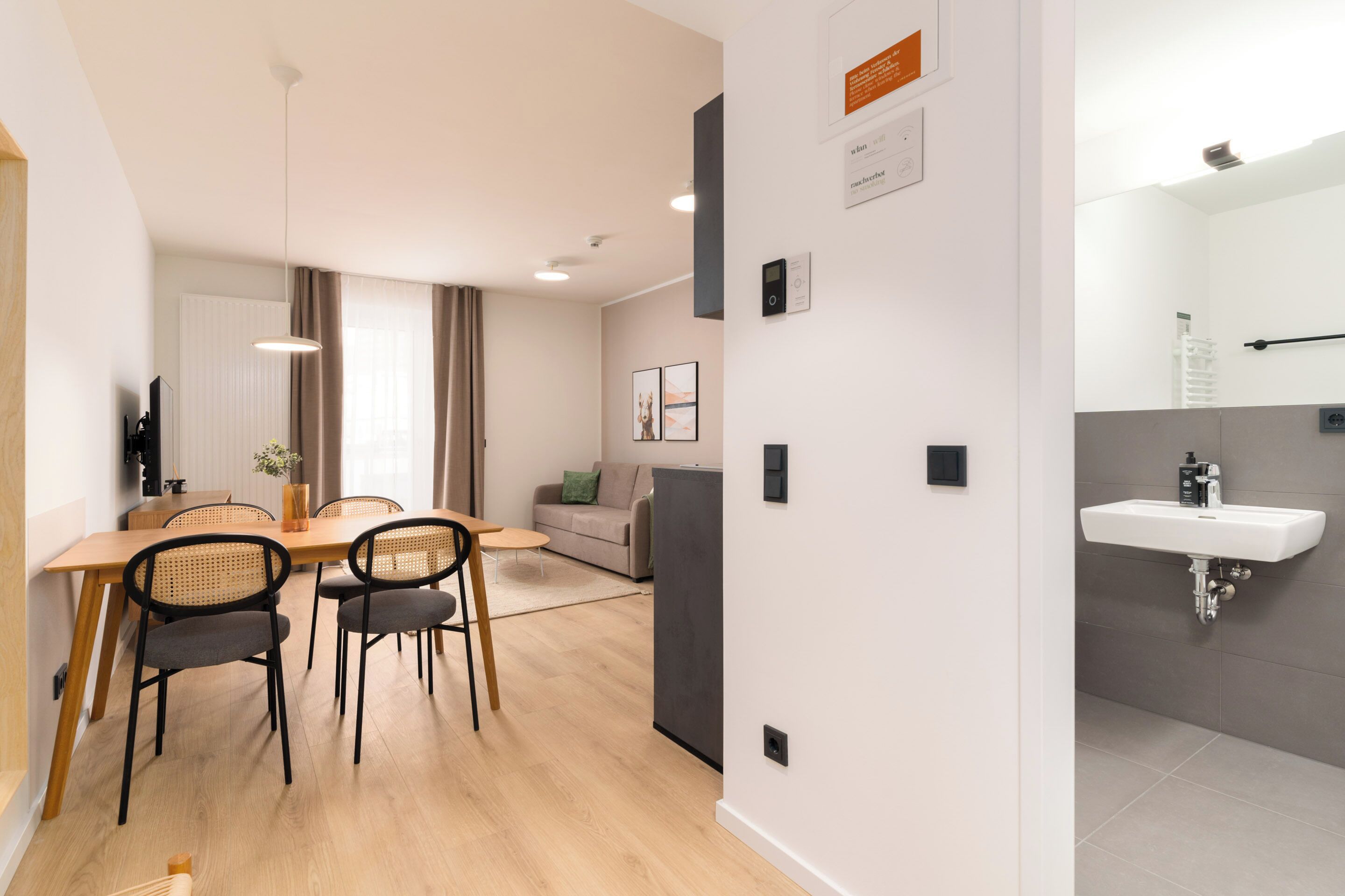 A modern living room with a dining area, a sofa, and a kitchen area with a sink.