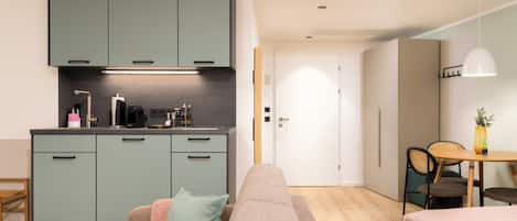 A modern kitchen with teal cabinets, a dining area with a table and chairs, and a cozy seating area with a sofa and cushions.