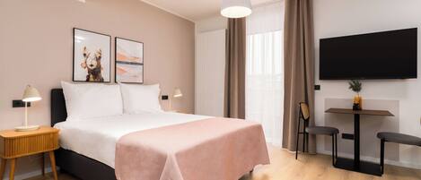 A modern hotel room with a bed, bedside tables, a TV, and a small table with chairs.