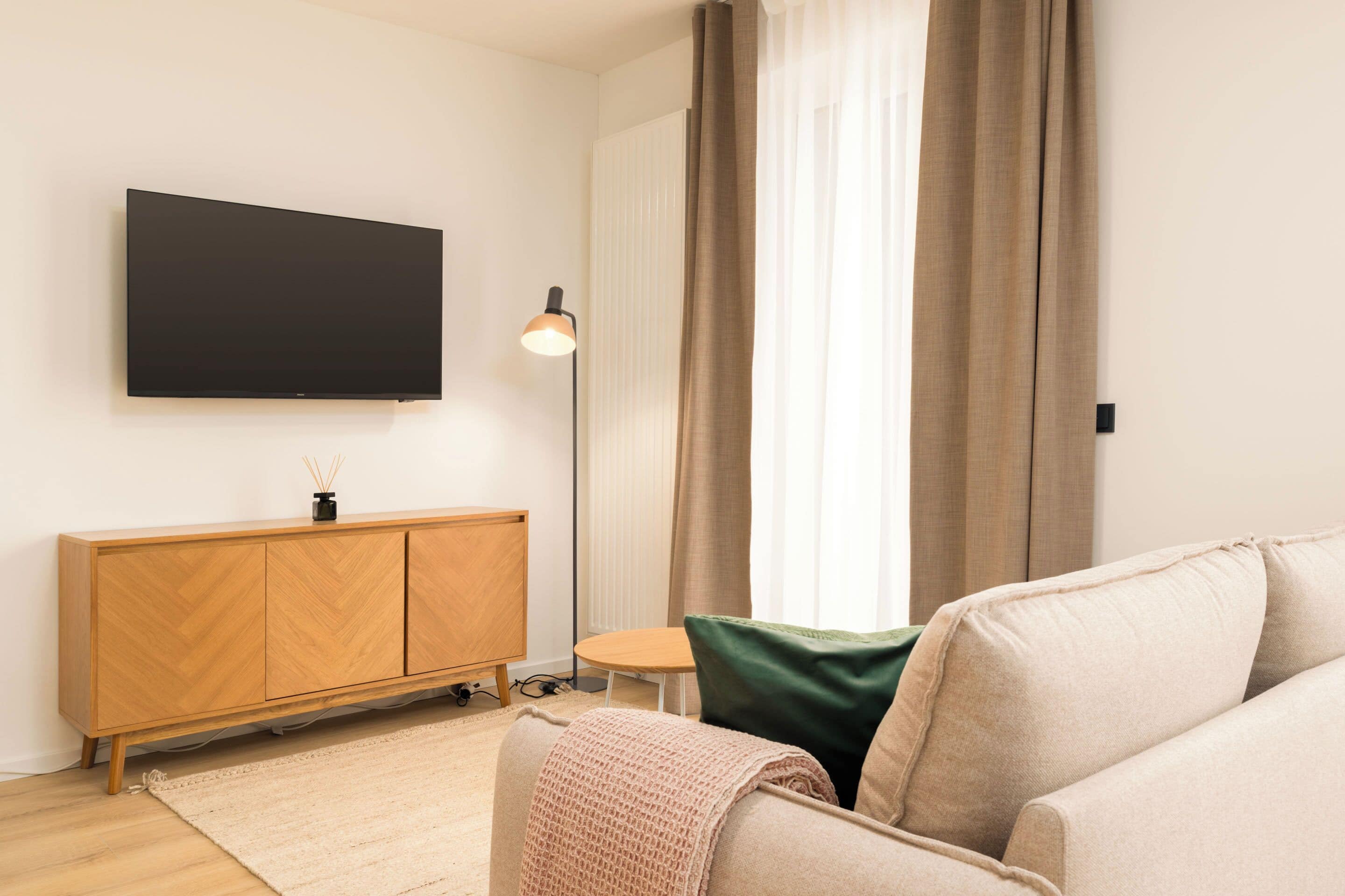 Een moderne woonkamer met een flatscreen televisie, een houten kast en een gezellige bank.