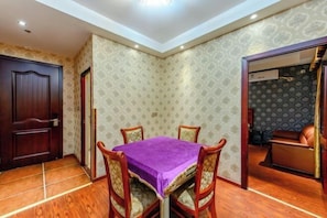 Un comedor con una mesa y sillas, un papel tapiz decorativo y una puerta que da a otra habitación.