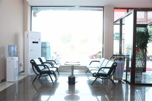 A reception area with a water dispenser, chairs, and a view through a glass door.