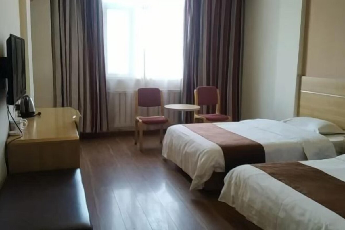 A hotel room with a bed, a desk, a chair, and a TV.