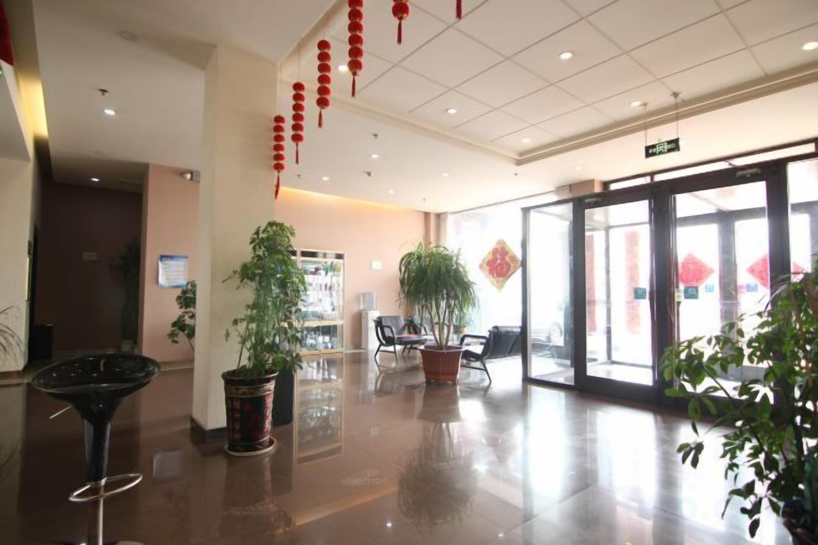 A hotel lobby with a reception desk, seating area, and potted plants.