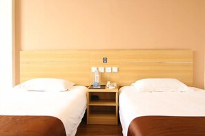 A hotel room with two single beds, a wooden headboard, a nightstand with a phone and a small table, and a wall-mounted power outlet. - Thank You Junyi Inn Huozhou Gulou (Huozhou)