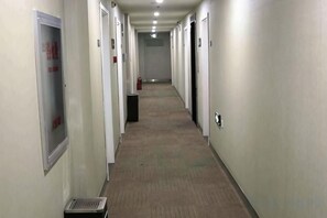 A long, narrow hallway with doors on both sides, a fire extinguisher, and a vent on the left. - Thank You Junyi Inn Huozhou Gulou (Huozhou)