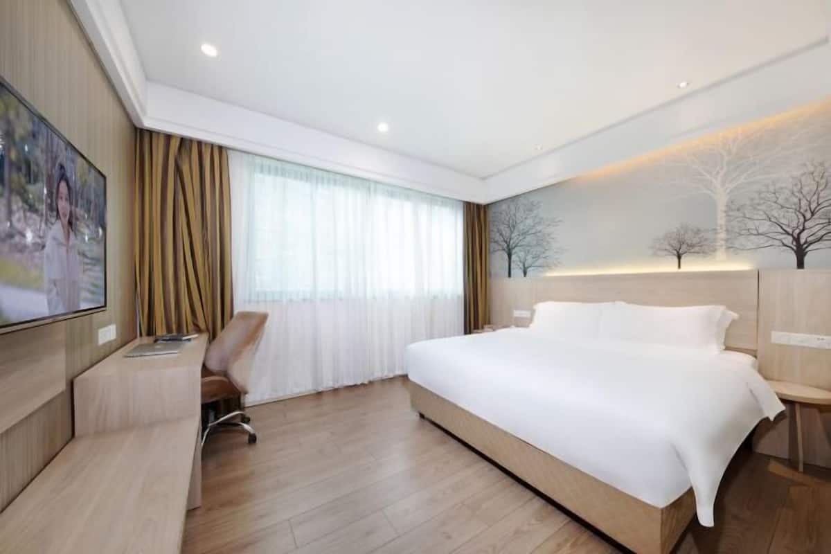 Habitació d'hotel moderna amb un llit gran, una taula de treball i un televisor.
