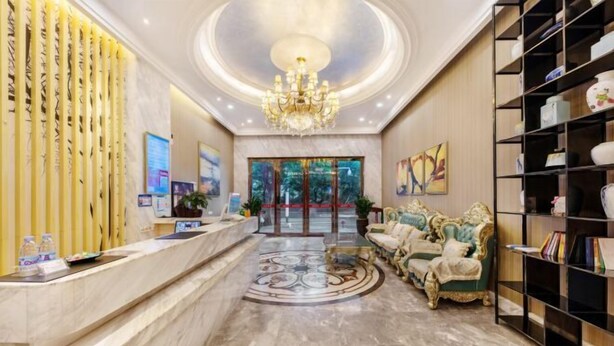 Et hotel lobby med reception, lysekrone, sofa og bogreol.