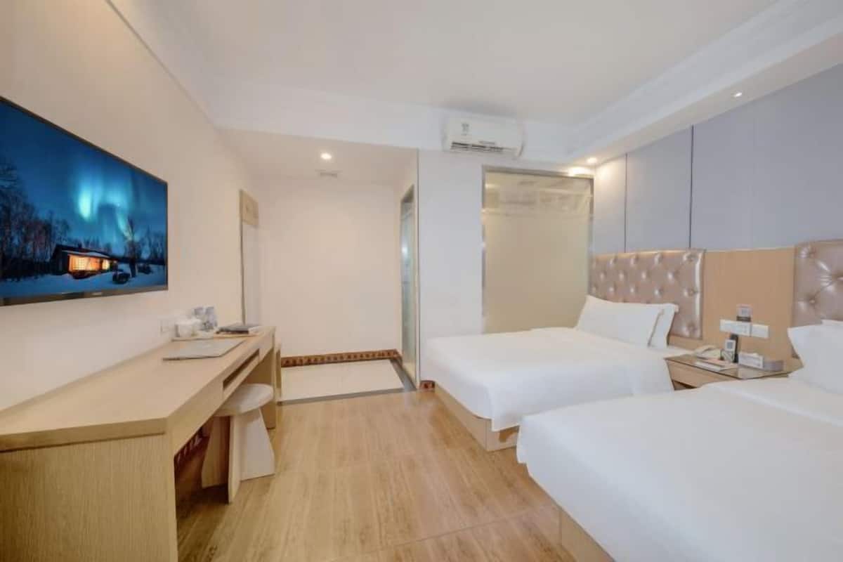Habitació d'hotel amb escriptori, dos llits, un quadre gran i vista del cel nocturn.