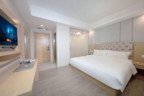 A modern hotel room with a large bed, a flat-screen TV mounted on the wall, a wooden desk, and a door leading to another room. - Toronto Hotel (Majialong Hotel, Nantou Ancient Town) (Shenzhen)