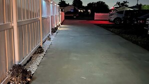 Un vialetto recintato che porta a una casa con cancello rosso e un'auto parcheggiata.